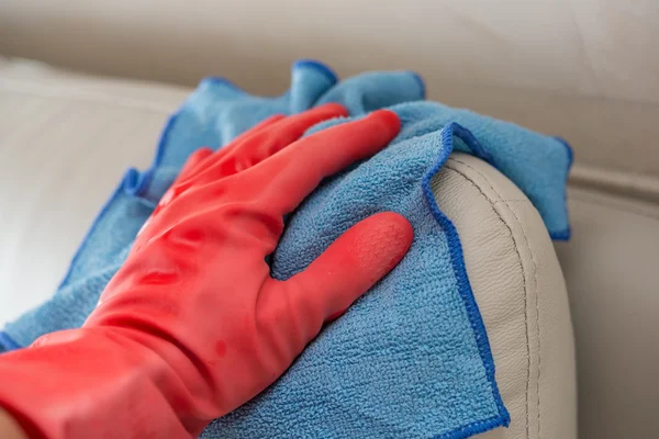 Cleaning leather sofa with blue cloth at home