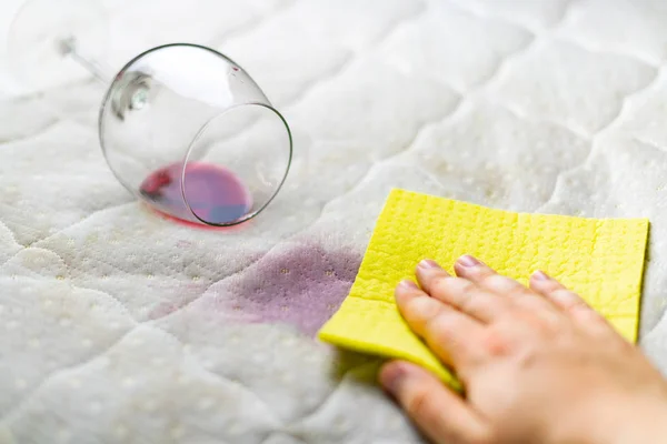 Cleaning wine stains on the white couch using cloth close up