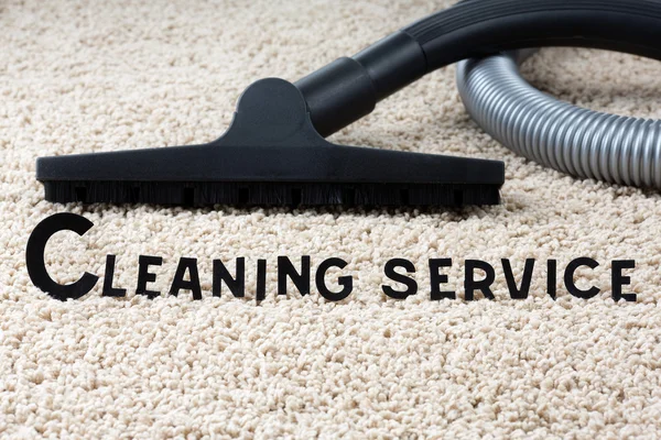 Close-up of steam cleaner and text "cleaning service" with a carpet as a background.