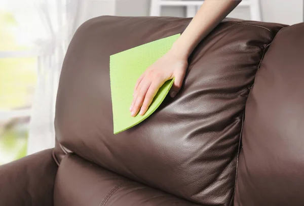 Close up shot of womans hand wiping brown leather sofa concept of sofa cleaning