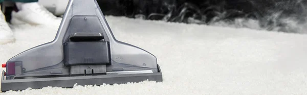 Close-up view of hot steam cleaning of white carpet with professional vacuum cleaner.