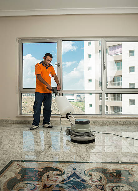 Manual worker cleaning the floor with buffer machine.