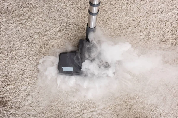 Top view of vacuum cleaner with hot steam on the carpet.