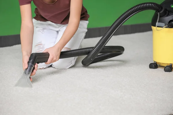 Woman using a steam cleaner on carpet, close-up.