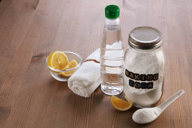 Natural cleaning ingredients - jar of baking soda, bottle of vinegar and lemon