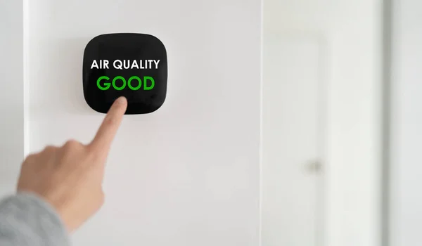 Air quality smart home domotic automation system. Hand pointing touchscreen air purifier filter at GOOD green level banner. 