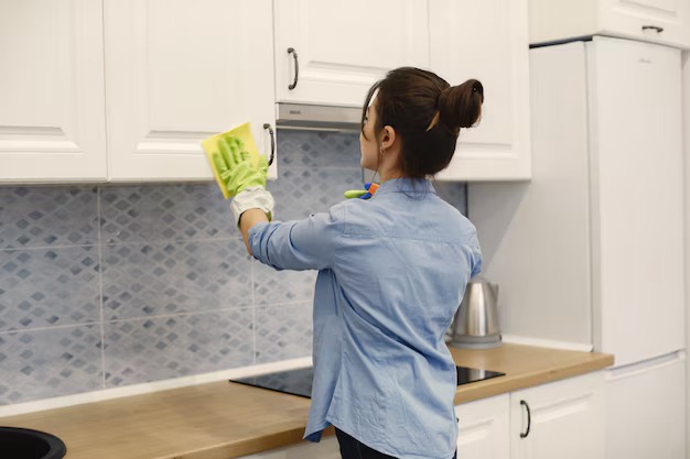 Woman cleaning kitchen cabinets.