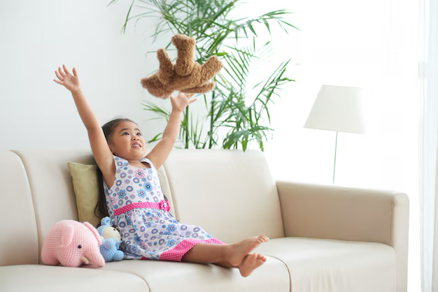 Girl playing with soft toys on a sofa.