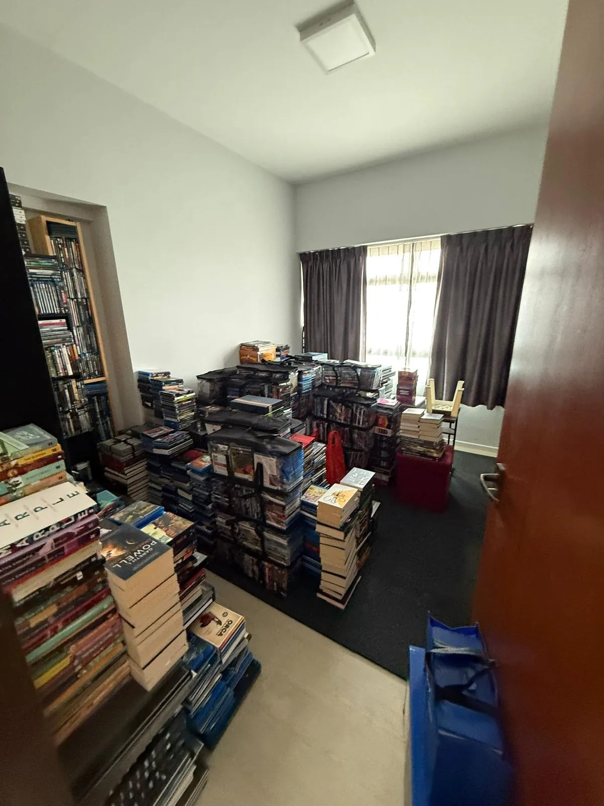 Living area filled with stacks of books and board games before the project