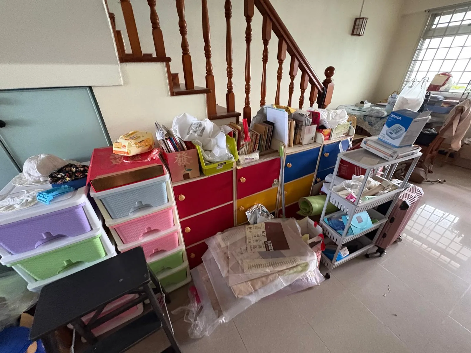 Staircase and entryway before decluttering, with colourful storage drawers buried under belongings