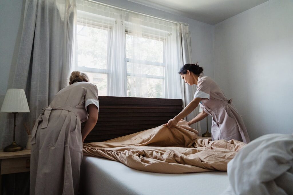 Woman in Brown and White Uniform Fixing Brown Bed Blanket